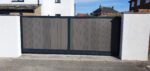 Flat top composite sliding driveway gate with grey composite boards and aluminium frame installed between white rendered walls