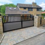 Flat top composite driveway gate with open-top metal bars and solid composite panels