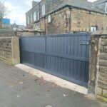 Flat top composite sliding gate with dark grey composite boards and aluminium frame installed between stone boundary walls