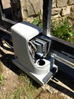Electric sliding gate motor installation with exposed wiring