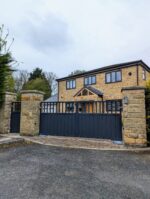 Flat top composite gate with open-top metal bars, fitted between stone pillars
