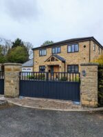 Composite driveway gate with a flat top rail installed at a residential property