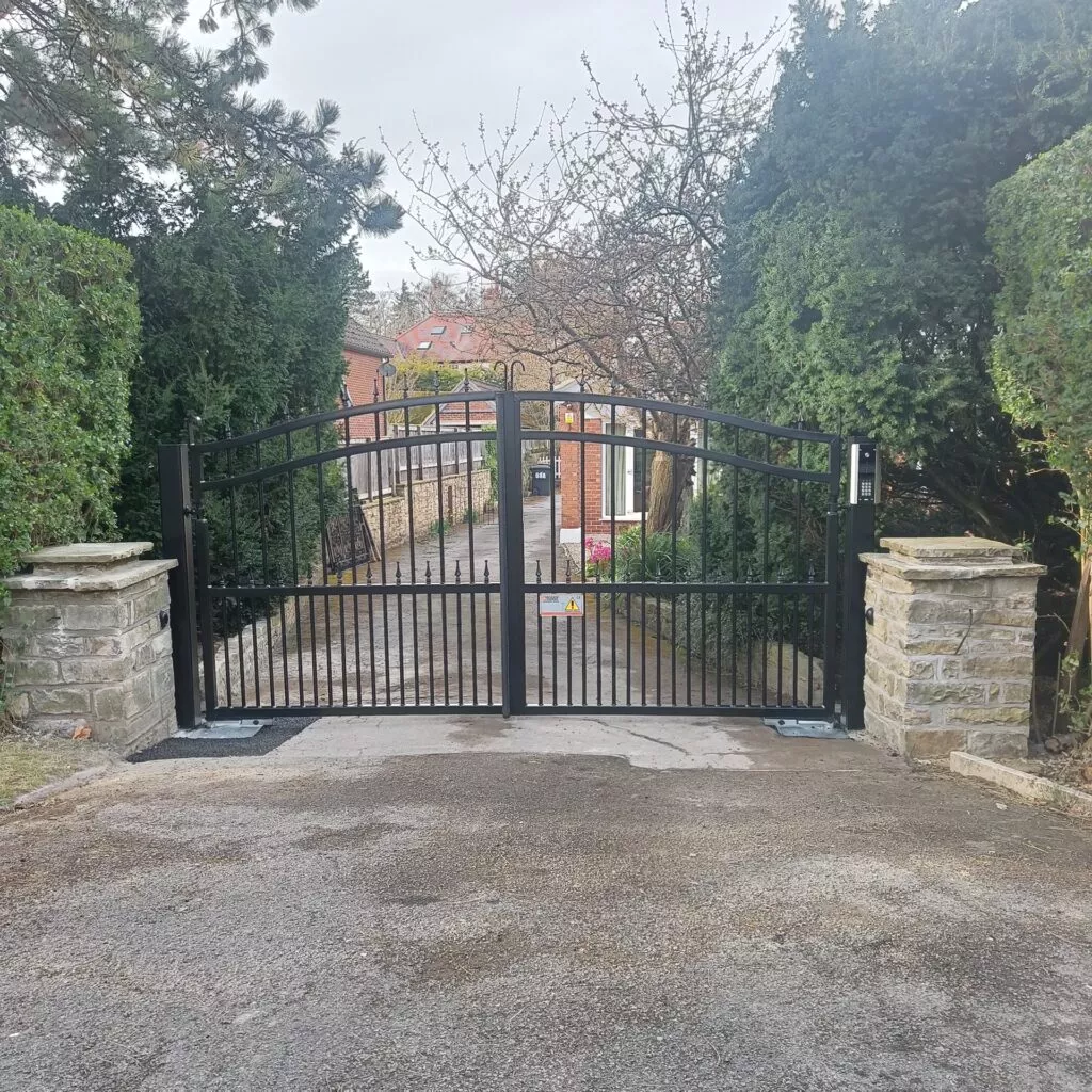 Black metal driveway gates installed between stone pillars at private residence